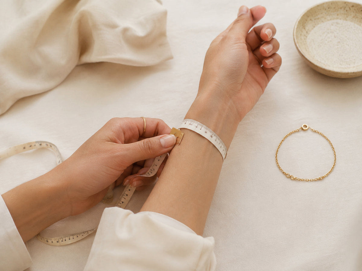 Hands measuring a wrist with a soft tape beside a bracelet