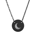 A black disc pendant necklace featuring a brushed silver crescent moon design in the center, suspended from a black link chain against a plain white background.